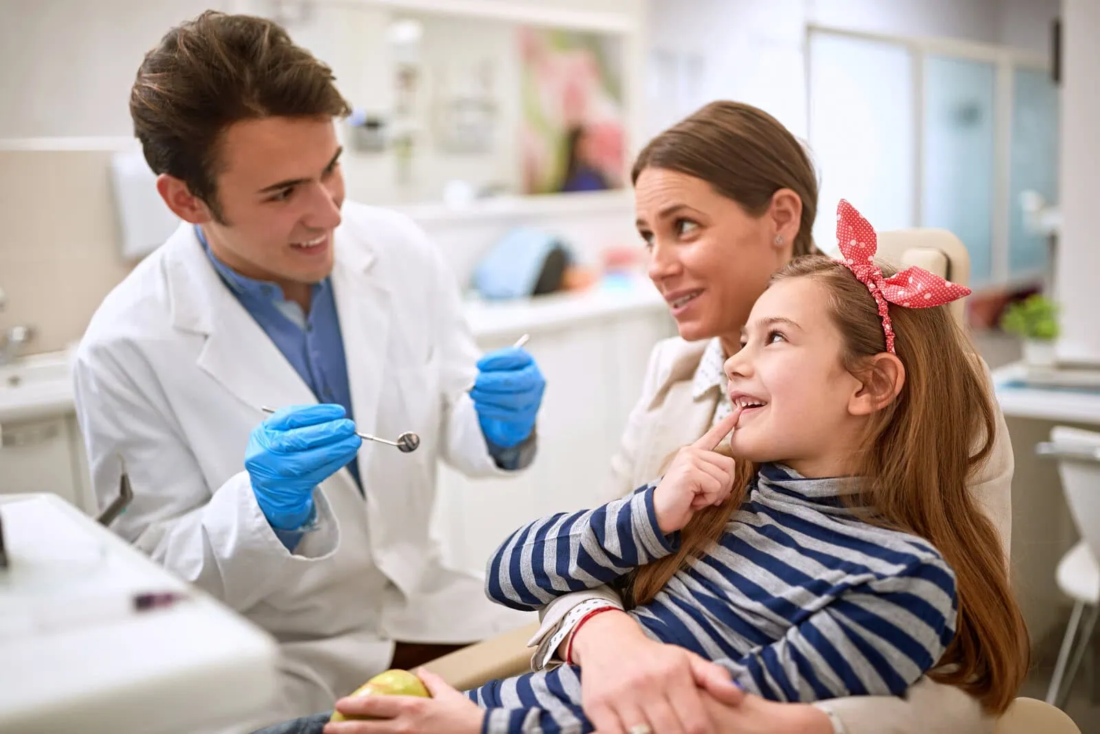 Dentist giving a smiling girl and her mom a friendly consultation